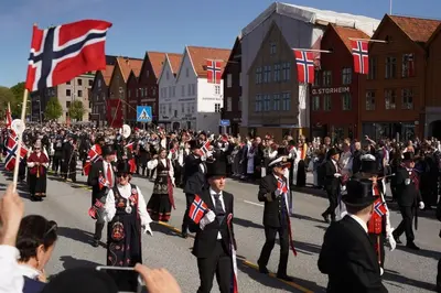 a group of people walking down a street with flags at Cosy house with sunny terrace, garden and fjord view in Bergen