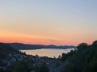 a view of a city and a lake at sunset at Cosy house with sunny terrace, garden and fjord view in Bergen