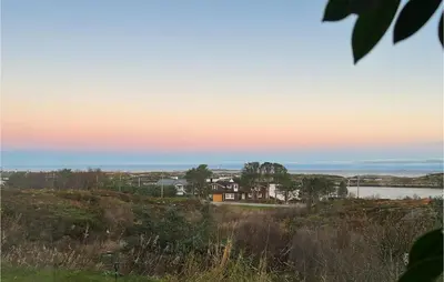 a house on a hill with a sunset in the background at Cozy Home In Vevang With Sauna in Vevang