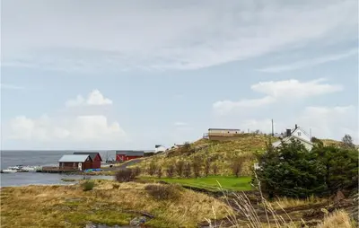 a house on top of a hill next to the ocean at Lovely Home In Smøla With Kitchen in Smøla