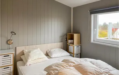 a bedroom with a bed with white sheets and a window at Lovely Home In Smøla With Kitchen in Smøla