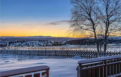a bench in the snow with the sunset in the background at 3 Bedroom Lovely Home In Vinstra in Vinstra