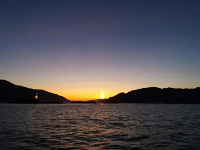 a sunset on the water with mountains in the background at 6 person holiday home in Huglo-By Traum in Nordhuglo