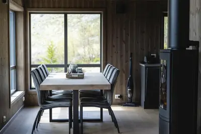 a table and chairs in a kitchen with a window at Moderne ski-in & ski-out hytte i Valdres, Norge - alt inkludert for ditt fjelleventyr in Aurdal