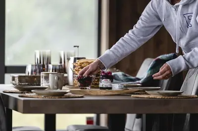 a person is serving food on a table at Moderne ski-in & ski-out hytte i Valdres, Norge - alt inkludert for ditt fjelleventyr in Aurdal