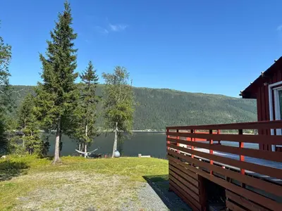 a fence in front of a house with a view of a lake at 9 person holiday home in Mosvik-By Traum in Mosvik