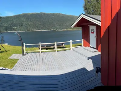 a large wooden deck with a bench on the side of a lake at 9 person holiday home in Mosvik-By Traum in Mosvik