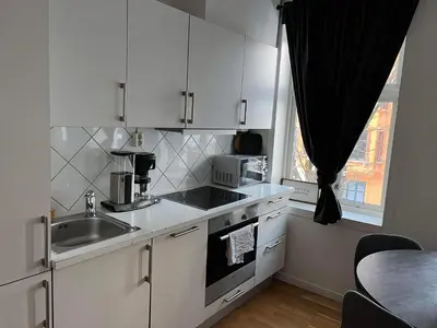 a kitchen with white cabinets and a sink and a window at Fløyen Apartment in Bergen