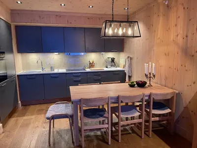 a kitchen with a wooden table and blue cabinets at Astonishing Mountain Lodge at the top of Gaustablikk, 25m2 west facing terrace, 3 bedrooms in Gaustablikk