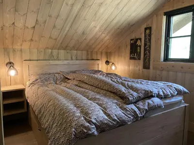 a bed in a room with a wooden ceiling at Beautifully styled mountain lodge with high standards, 10 minutes from Geilo in Geilo