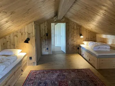 two beds in a room with wooden walls at Beautifully styled mountain lodge with high standards, 10 minutes from Geilo in Geilo