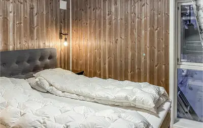 a bed in a room with a wooden wall at 3 Bedroom Gorgeous Home In Brøttum