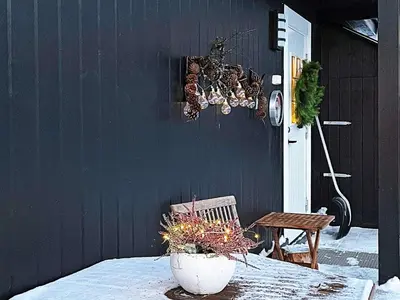 a black wall with a table with a plant in a vase at 7 person holiday home in Rauland-By Traum in Rauland