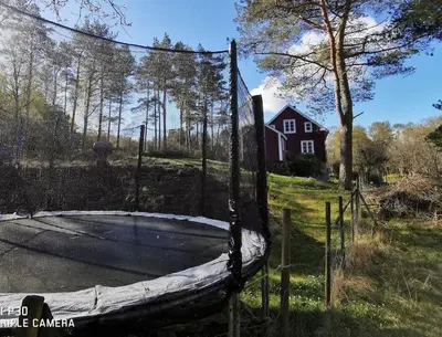 a basketball hoop in a yard with a house at Alone In The Woods With Your Own River Nearby in Fitjar