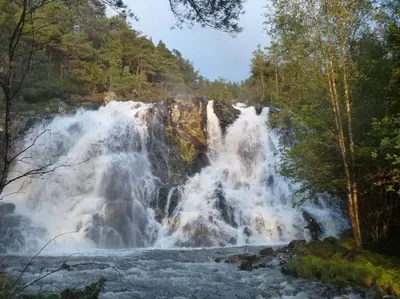 a person standing in front of a waterfall at Alone In The Woods With Your Own River Nearby in Fitjar