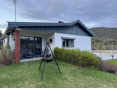 a small white house with a swing in the yard at Skogro ved Norefjell in Noresund