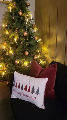 a christmas tree with a happy holidays pillow on a couch at Skogro ved Norefjell in Noresund