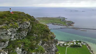 a person sitting on top of a mountain overlooking the ocean at Haramsøy Holiday Apartment- Island Life North in Haram