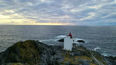 a lighthouse on a rock in the ocean at Haramsøy Holiday Apartment- Island Life North in Haram