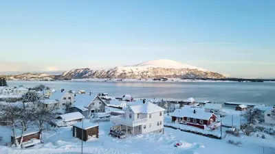 a town covered in snow with a mountain in the background at Haramsøy Holiday Apartment- Island Life North in Haram