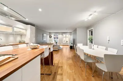 a kitchen and dining room with white tables and chairs at Fløyen Lux Apartment in Bergen