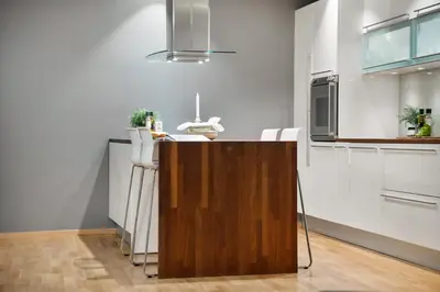 a kitchen with white cabinets and a wooden counter top at Fløyen Lux Apartment in Bergen