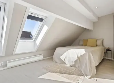 a attic bedroom with a bed and a window at Fløyen Lux Apartment in Bergen