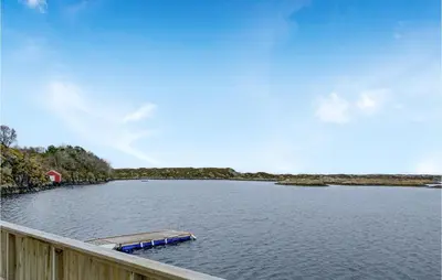 a boat in the water next to a wooden fence at Beach Front Home In Smøla With Kitchen in Smøla