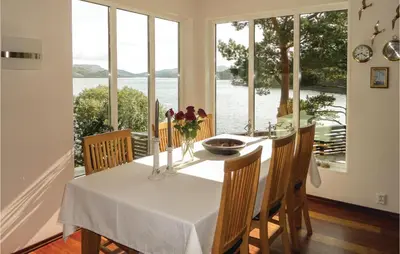 a dining room with a table and chairs and windows at Gorgeous Home In Sveio With Kitchen in Sveio