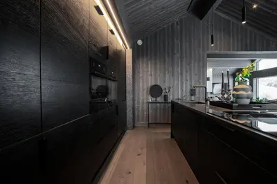 a kitchen with black cabinets and a wooden floor at The Panorama Retreat - Rindabotn Cabin in Sogndal