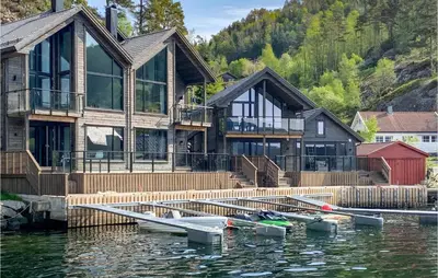 a house on the water with boats in the water at 3 Bedroom Awesome Home In Hebnes in Hebnes