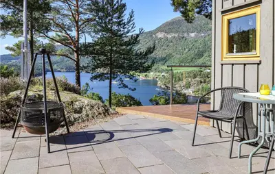 a patio with a table and chairs and a view of a lake at Beautiful Home In Hebnes With Kitchen in Hebnes