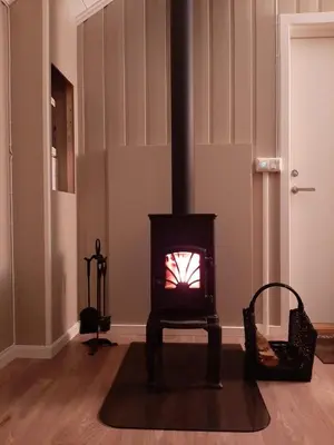 a black stove in a room with a floor at Kleines Haus am Fjord in Sør-Eidem