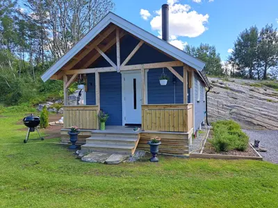 a blue tiny house with a porch and stairs at Kleines Haus am Fjord in Sør-Eidem
