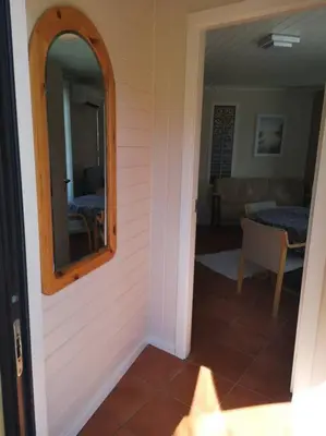 a hallway with a mirror and a room with a table at Strøken leilighet in Åheim