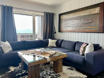 a living room with a blue couch and a wooden table at Bjelbølens stjernely in Beitostøl