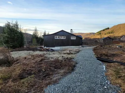 a house in a field with a gravel road at Tangen - cabin with 4 bedrooms - great nature in Norheimsund