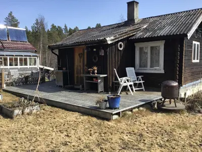 a small cabin with a deck and a grill at Furuly vakantiehuis in Vingelen