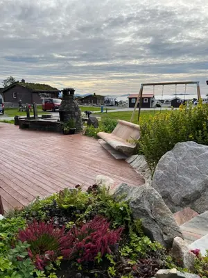 a patio with a swing and some flowers and rocks at Bud Camping in Bud