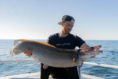 a man holding a large fish on a boat at Bud Camping in Bud