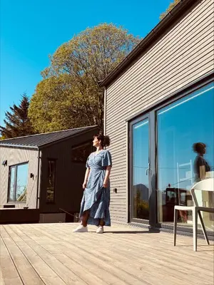 a woman in a blue dress walking past a building at Kråen Gard in Larsnes