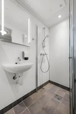 a white bathroom with a sink and a shower at Norpark Romutleie in Orkanger