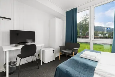 a bedroom with a bed and a desk and a television at Norpark Romutleie in Orkanger