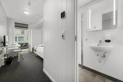 a bathroom with a sink and a bedroom with a bed at Norpark Romutleie in Orkanger