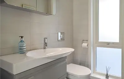 a white bathroom with a sink and a toilet at 4 Bedroom Cozy Home In Fitjar in Fitjar