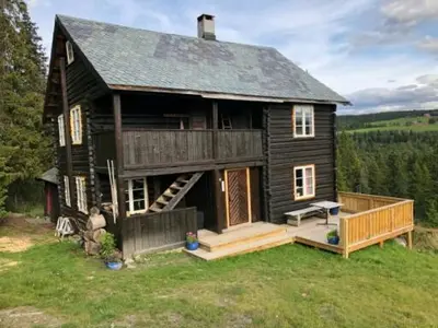 a large wooden house with a porch and a deck at Nedre Skogtun cabin by Norgesbooking in Tisleidalen