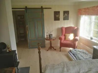 a living room with a chair and a door at Nedre Skogtun cabin by Norgesbooking in Tisleidalen