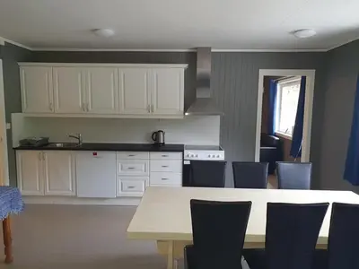 a kitchen with white cabinets and a table and chairs at Leirvik i Sogn-Apartment in Leirvik