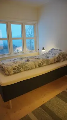 a bed sitting in a room with two windows at Moonvalley Lodge - stort & koselig hus - Måndalen in Sæbø