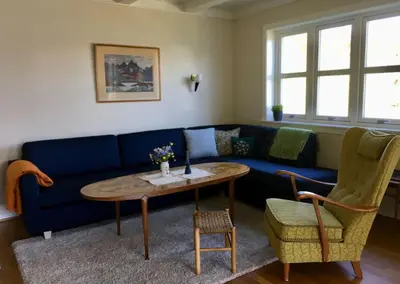 a living room with a blue couch and a table and chairs at Moonvalley Lodge - stort & koselig hus - Måndalen in Sæbø